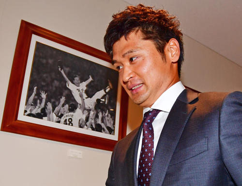 阪神入団会見を終え星野仙一氏の胴上げ写真の前を通り引き揚げる中田賢一（撮影・清水貴仁）