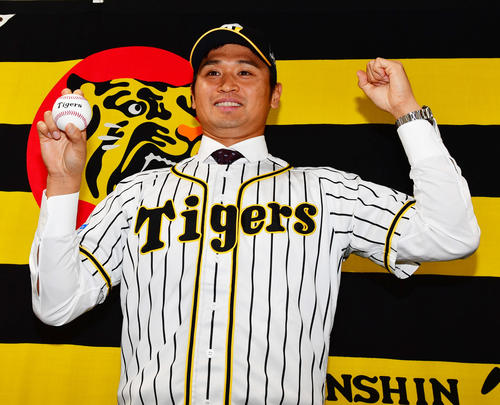 阪神入団会見でユニホームに袖を通し笑顔をみせる中田賢一（撮影・清水貴仁）