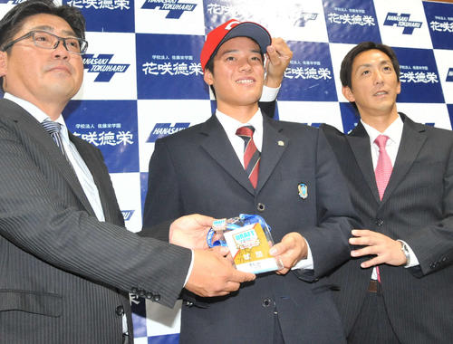 ドラフト会議の関係者パスを手に、広島スカウト陣と記念撮影する韮沢内野手（中央）。パスには佐々岡新監督の直筆サインが書かれている（撮影・山岸章利）