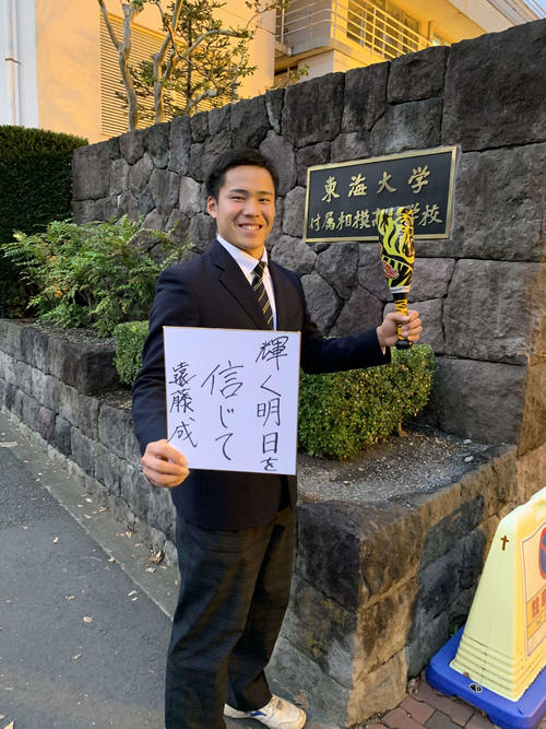 阪神ドラフト4位の東海大相模・遠藤は指名あいさつを受け、校門の前で座右の銘を書いた色紙を手に笑顔を見せる（撮影・只松憲）