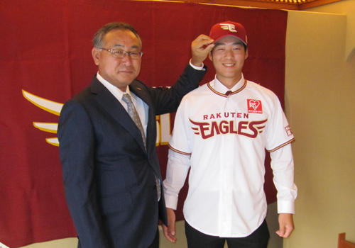 楽天から育成ドラフト3位で指名されたハワイ大・山崎（右）は入団合意し、後関スカウト部長から帽子とユニホームを渡され笑顔