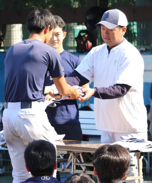 早慶戦を翌日に控えた練習後、慶大・大久保監督（右）はメンバーにユニホームを手渡す（撮影・古川真弥）
