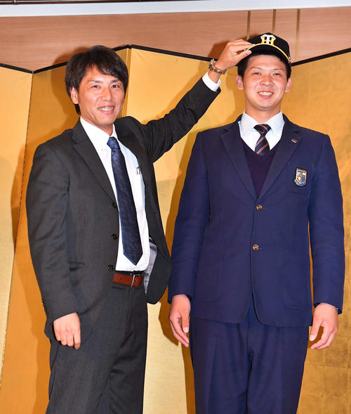 阪神との仮契約を終え、渡辺スカウト（左）に帽子をかぶせてもらい笑顔を見せる履正社・井上（撮影・上田博志）