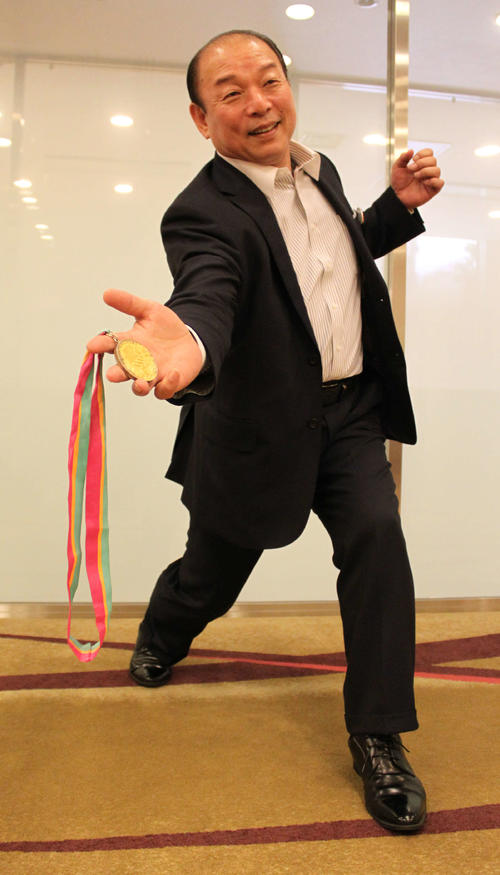 ロス五輪の金メダルを手に下手投げのフォームを披露する吉田幸夫さん