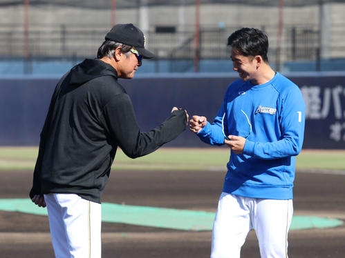 練習前に荒木2軍監督兼投手コーチ（左）とグータッチを交わす日本ハム斎藤（撮影・山崎純一）