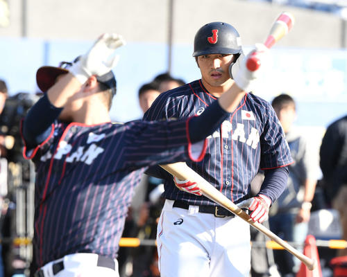 坂本勇（手前）のティー打撃を見つめる鈴木（撮影・山崎安昭）