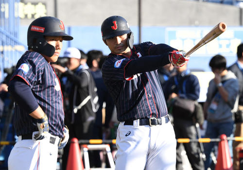 バットを見つめる鈴木。左は吉田正（撮影・山崎安昭）