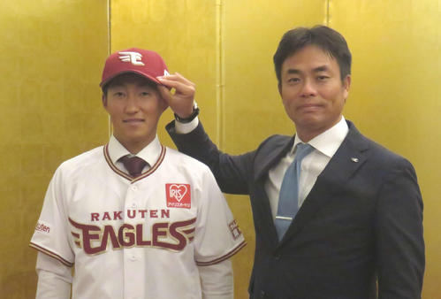 楽天ドラフト1位の大阪ガス・小深田（左）は入団交渉を終え、金屏風をバックにユニホーム姿で愛敬スカウトと記念撮影（撮影・桑原幹久）