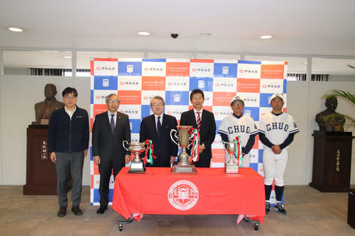 東都大学野球リーグ優勝報告会・第50回記念明治神宮野球大会壮行会にて優勝トロフィーを前に記念撮影をする野球部スタッフ。（写真左3人目から福原部長、清水監督、平田コーチ、美馬コーチ）（撮影・保坂淑子）