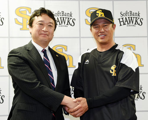 入団会見で三笠GM（左）と握手を交わす平石打撃兼野手総合コーチ（撮影・今浪浩三）