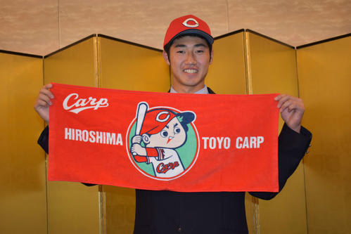 仮契約を終え、広島カープのタオルを掲げ写真撮影に応じるドラフト3位の霞ケ浦・鈴木寛