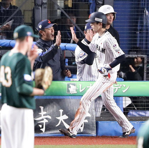 日本対オーストラリア　7回裏日本2死三塁、源田のセーフティーバントで同点の生還をした周東（手前）を笑顔で迎える稲葉監督（奥）（撮影・浅見桂子）