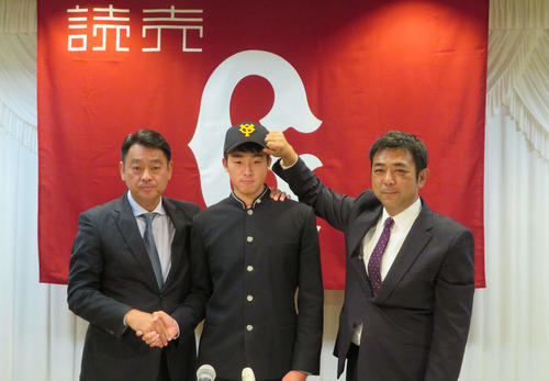 巨人仮契約　長谷川スカウト部長（左）と握手をするドラフト1位の青森・堀田賢慎。右は柏田スカウト（撮影・湯本勝大）