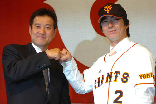 06年12月、巨人のユニホームに腕を通した小笠原は原監督とグータッチ