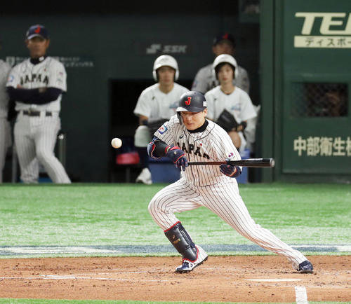 日本対韓国　3回裏日本無死二塁、セーフティーバントで出塁する丸。左端は見つめる稲葉監督（撮影・前田充）