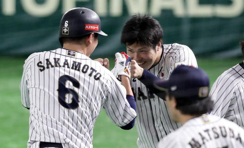 日本対韓国　7回裏日本2死三塁、浅村の適時打で生還した坂本勇（手前）を笑顔で迎える甲斐野（撮影・浅見桂子）