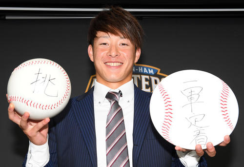 ボールには今年思った一文字、色紙には来季の目標を記し、笑顔を見せる日本ハムの吉田（撮影・たえ見朱実）