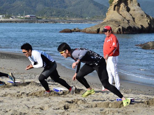 砂浜でチーム対抗リレー走を行う広島ナインを笑顔で鼓舞する佐々岡監督（右）