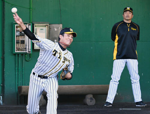 山本昌臨時コーチ（右）が見守る仲、ブルペンで投球練習を行う藤浪（撮影・前岡正明）