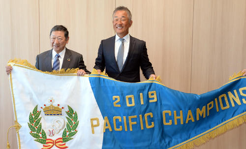 西武辻監督（右）は後藤オーナーと笑顔でチャンピオンフラッグを掲げる（撮影・鈴木正章）