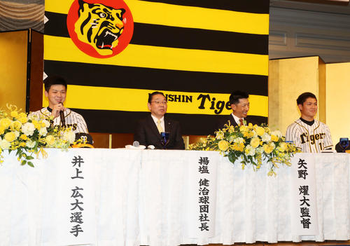 新人入団会見であいさつする井上（左）に笑顔を見せる矢野監督（右から2人目）、右端は西純、左から2人目は揚塩社長（撮影・加藤哉）