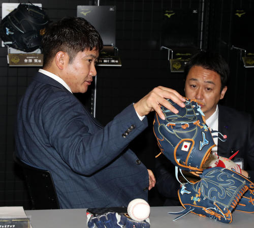ミズノブランドアンバサダー会議で日の丸が内側に刺繍されたグラブを手に取る菅野（撮影・加藤哉）