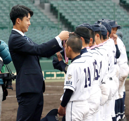 小幡（左）はタイガースカップ表彰式のプレゼンターを務め少年たちにメダルを授与する（撮影・上山淳一）