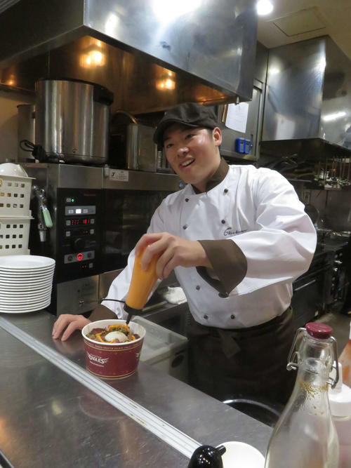 「6KenKitchen」でのイベントでシェフ姿の楽天松井は、ローストビーフ丼にソースをかける（撮影・桑原幹久）