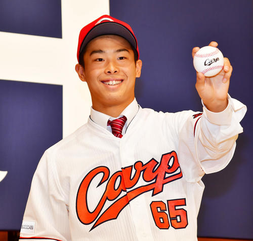 広島の新入団選手発表でユニホームに袖を通す玉村昇悟（撮影・清水貴仁）