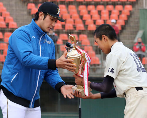 大会後の表彰式で優勝チームの選手にトロフィーを手渡す日本ハム大田（撮影・山崎純一）