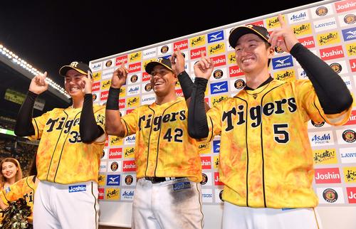 プロ初勝利を挙げた阪神浜地（左）がお立ち台で笑顔でポーズ（2019年7月30日）