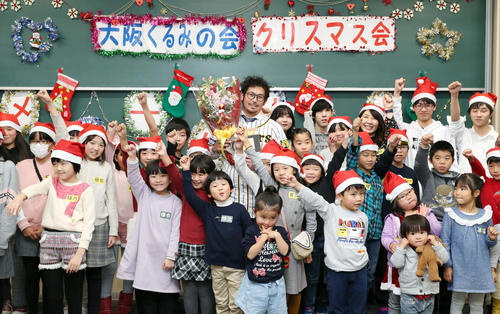 大阪くるみの会・クリスマス会に参加した子どもたちと笑顔で記念撮影を行う阪神岩田（中央）（撮影・前田充）