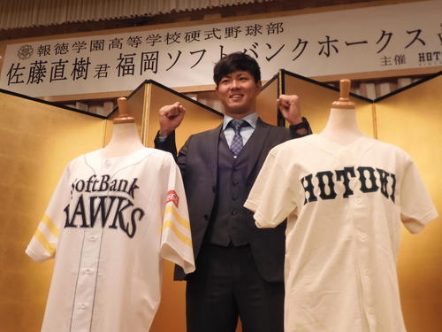ソフトバンクのドラフト1位佐藤直樹は、報徳学園とソフトバンクのユニホームを前に笑顔を見せる