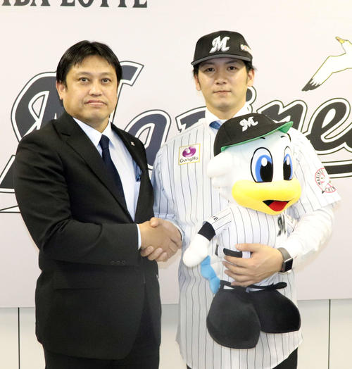 ロッテ松本球団本部長（左）と握手をかわす、楽天から人的補償で移籍した小野（撮影・久永壮真）
