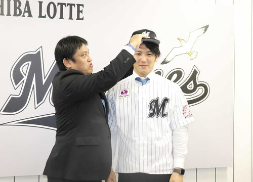 楽天から人的補償で移籍し、ロッテ松本球団本部長（左）に帽子をかぶせてもらう小野（撮影・久永壮真）