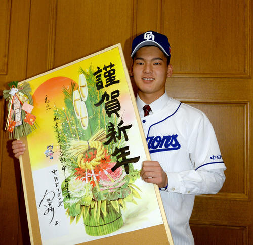 真新しいサインを記した年賀状を手に笑顔の石川（撮影・森本幸一）