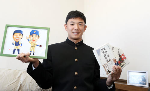 入寮し、星稜の山下名誉監督が持たせてくれた野村氏らの本と、山瀬とのバッテリーの似顔絵を手に笑顔を見せるヤクルト奥川（撮影・狩俣裕三）