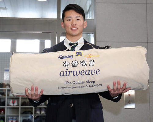 入寮したロッテドラフト4位横山は持参した刺繍入りのケースに入ったエアウィーブを手に写真に納まる（撮影・垰建太）