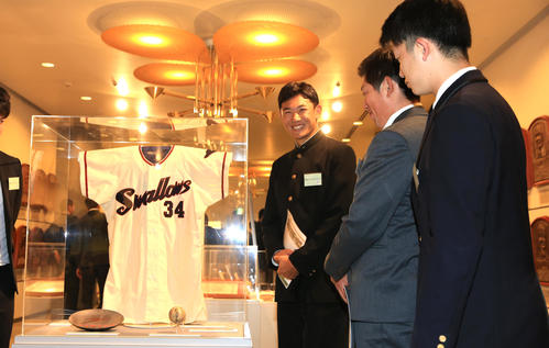 展示された故・金田正一氏のユニホームに笑顔を見せる奥川（左）らヤクルトの新人選手たち（代表撮影）