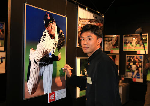展示された自身の写真にサインするヤクルト奥川恭伸（代表撮影）
