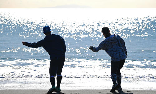 きらめく海に向かって石を投げる巨人今村（右）と高橋（撮影・加藤諒）