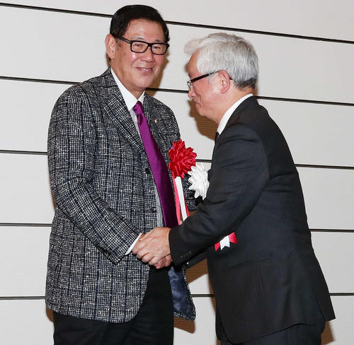 お祝いのスピーチを終えた山中氏（右）と握手する田淵氏（撮影・丹羽敏通）