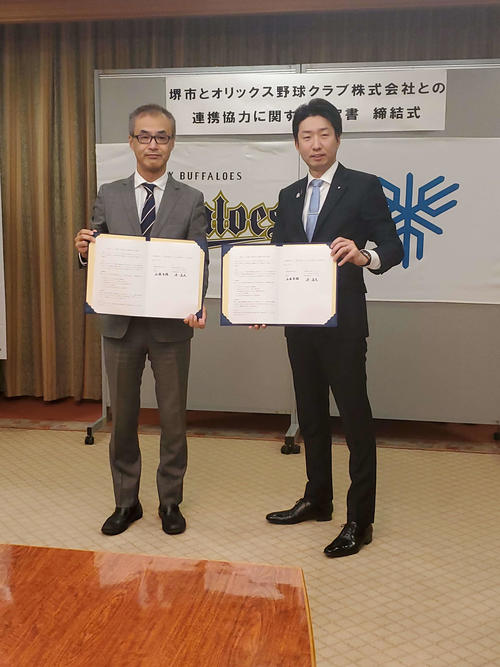 オリックス湊通夫球団社長は堺市との連携協定締結式に臨み、永藤英機堺市長（右）と調印書を持つ