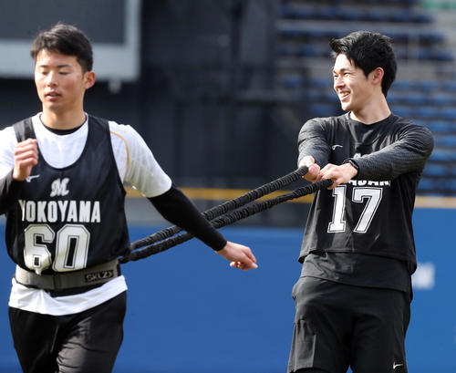 ロッテ新人合同自主トレで走り込む横山（手前）のロープを手に笑顔を見せる佐々木朗（撮影・垰建太）