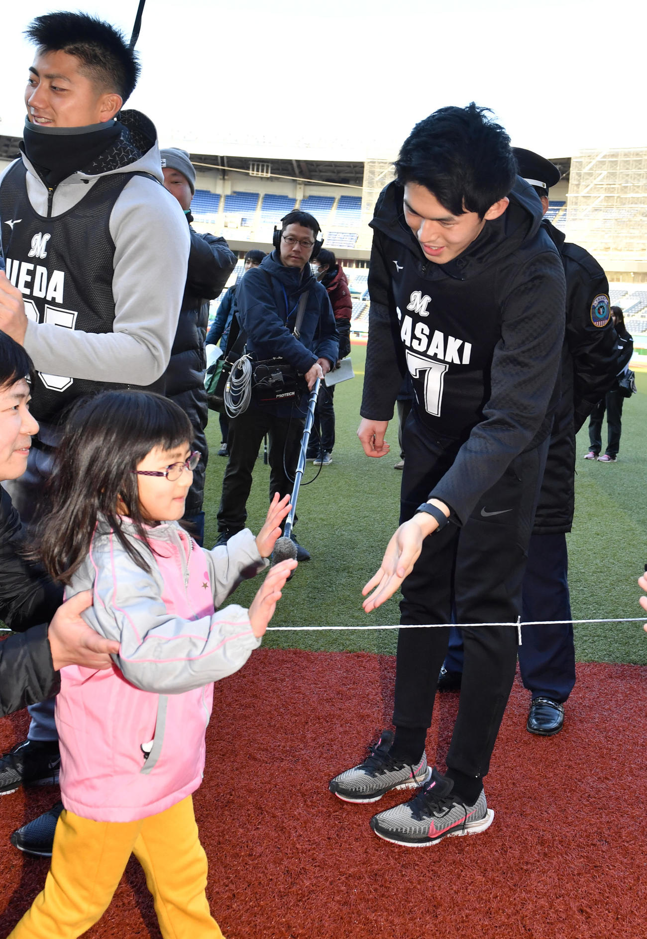 新人合同自主トレを終えた佐々木朗（右）は約600人とハイタッチする（撮影・柴田隆二）