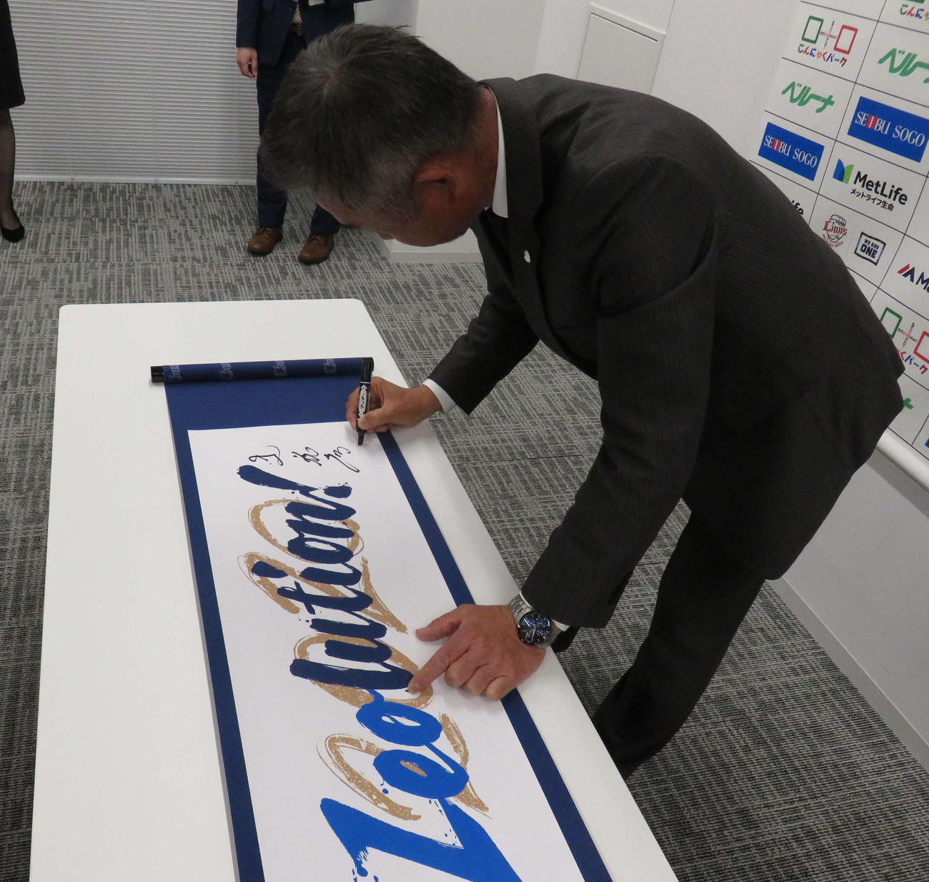 新スローガン「Leolution！」の巻物にサインをする西武辻監督（撮影・栗田成芳）