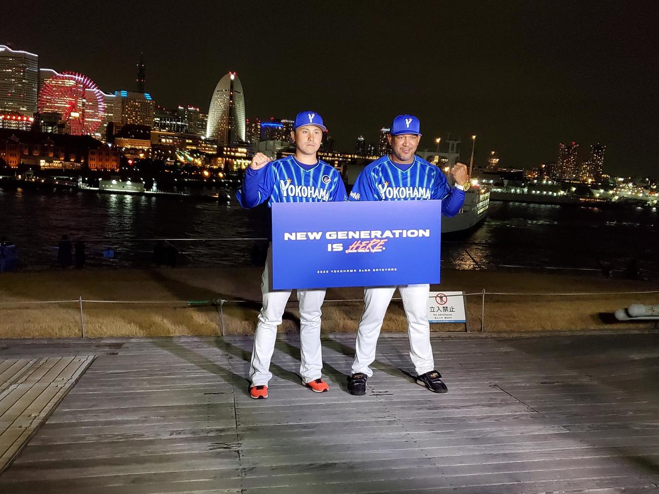 DeNA新主将に就任した佐野はラミレス監督とともに、今季のチームスローガンを掲げて横浜の夜景の前でガッツポーズ（撮影・鈴木正章）