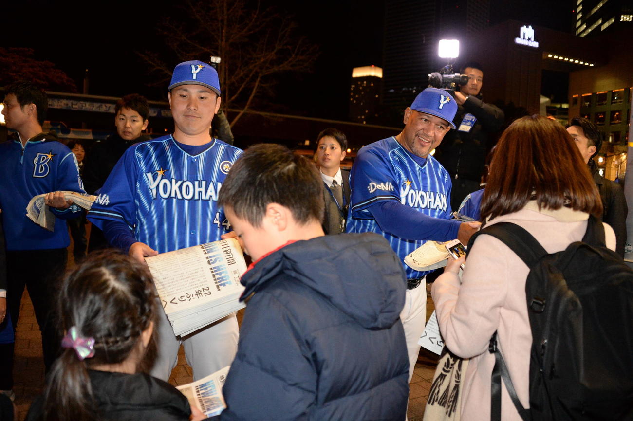 DeNA新主将に就任した佐野はラミレス監督とともにJR桜木町駅前で号外を配る（撮影・鈴木正章）