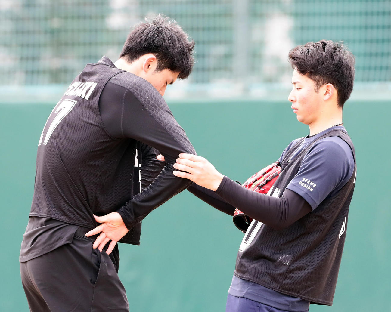 キャッチボール前、横山（右）から引っ張られながら肩胛骨を広げるロッテ佐々木朗希（撮影・浅見桂子）