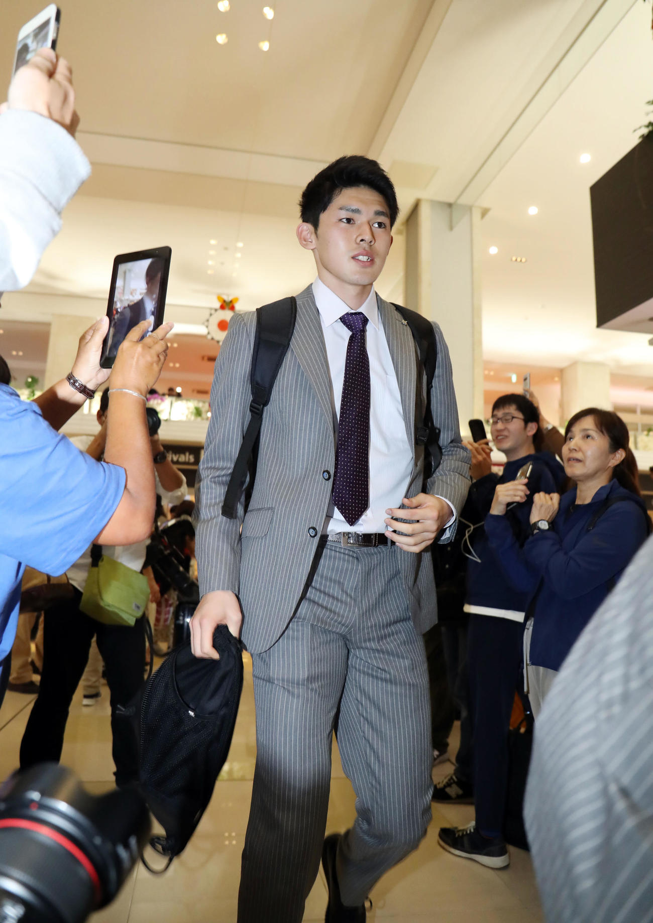 居合わせた観光客と報道陣の視線を浴びながら新石垣空港に到着したロッテ佐々木朗（撮影・垰建太）